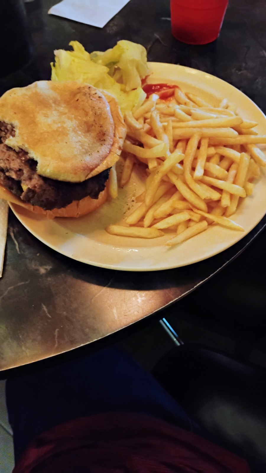 A hand-built burger beside a plate of fries.