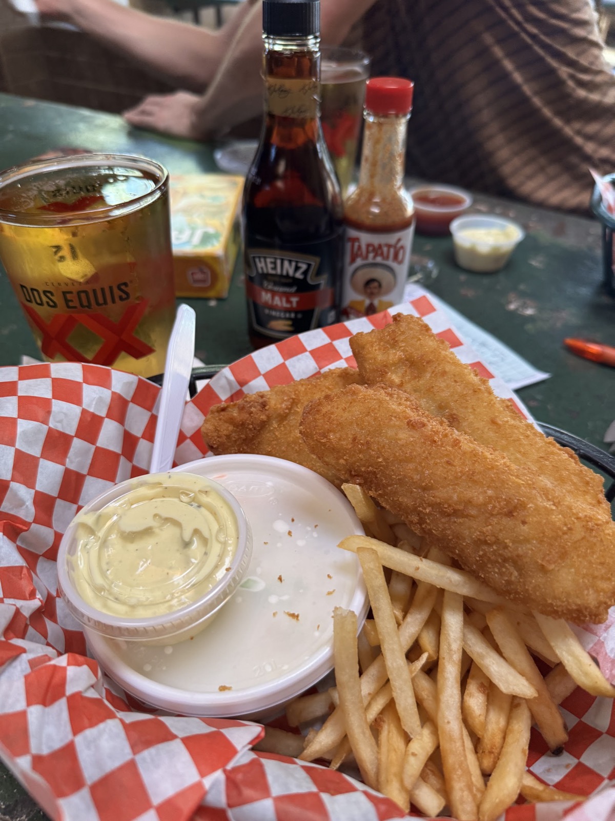 A basket of golden fried fish and fries with a cold beer.